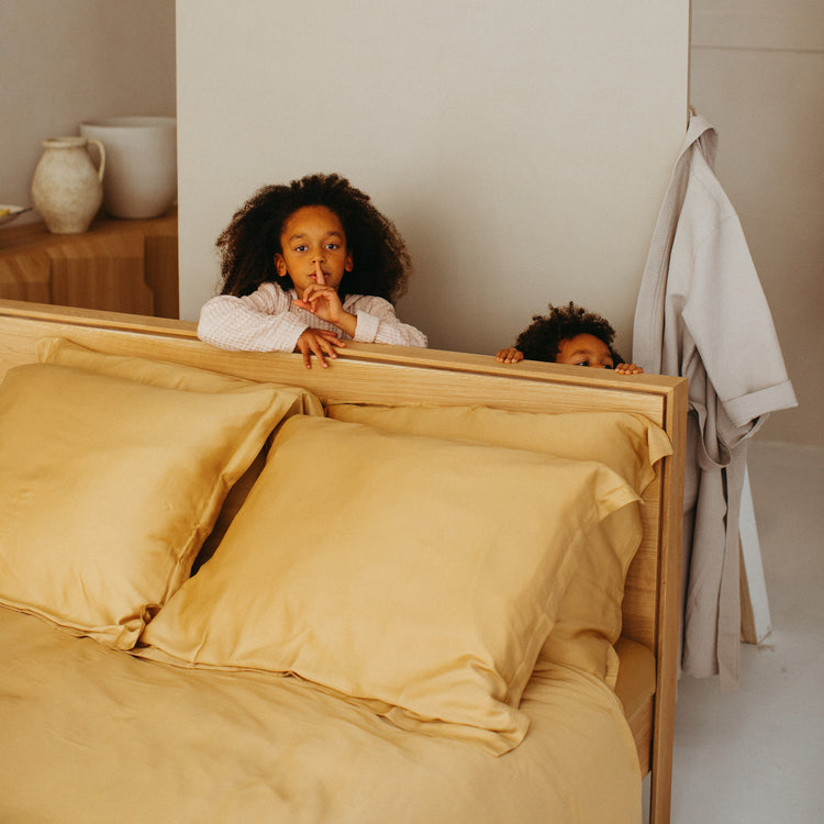 Kussenslopen van Eco Bamboe op een opgemaakt bed in slaapkamer met 2 lieve kindjes. De kussenslopen zijn super zacht voor de gevoelige huid.