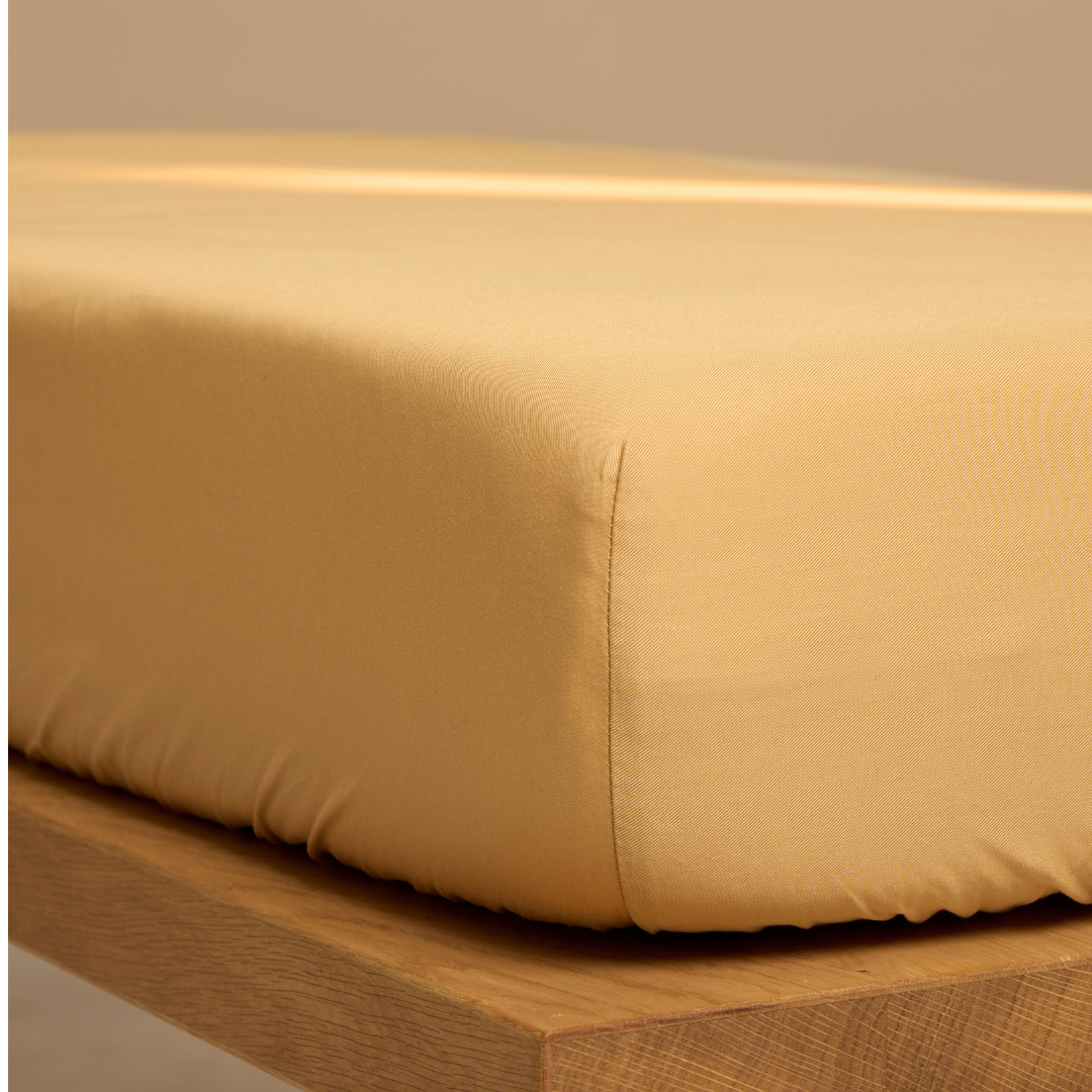 Een hoeslaken van Tencel Twill, ook wel lyocell, om een matras in de kleur okergeel.
