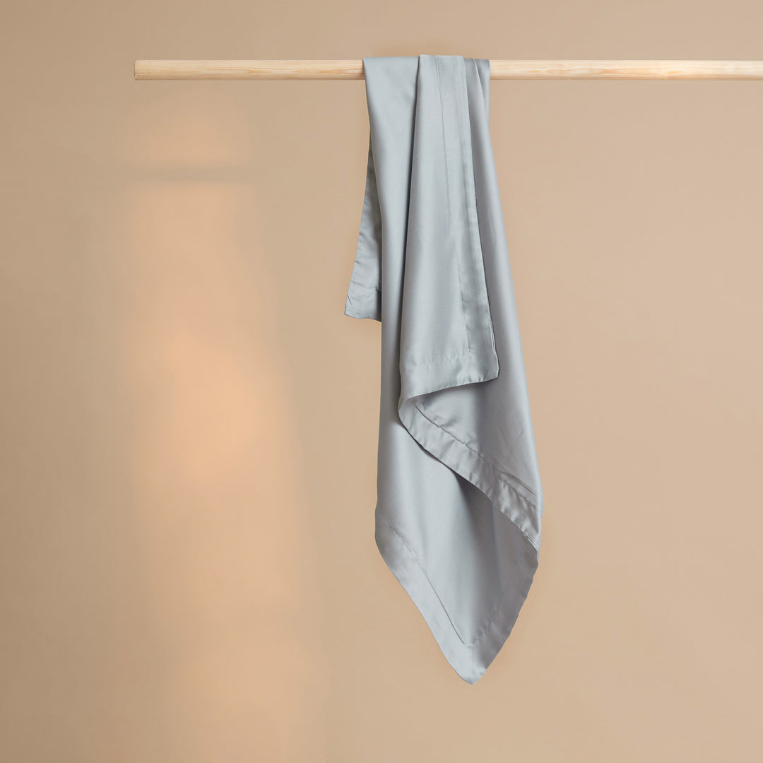 Tencel kussensloop in de kleur grijs blauw hangend aan een stok