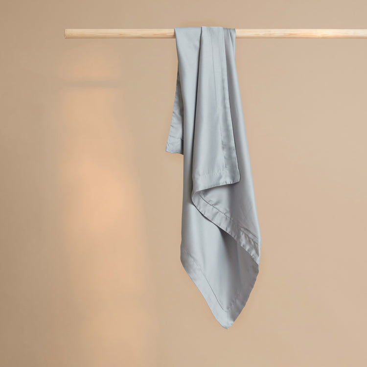 Tencel kussensloop in de kleur grijs blauw hangend aan een stok