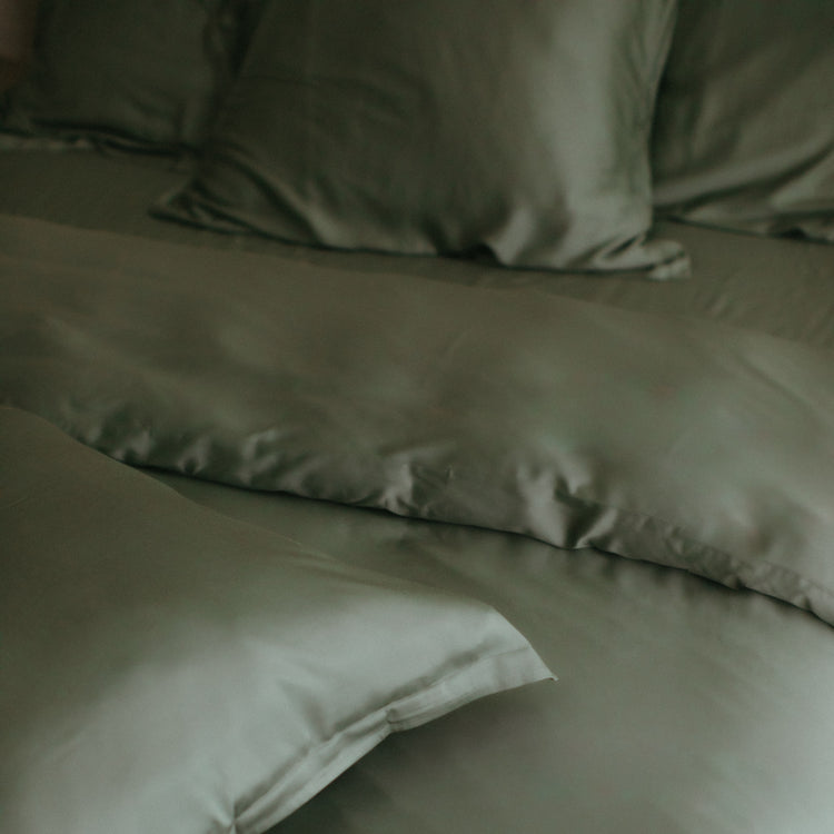 Detail foto van een bamboe opgemaakt bed in de kleur olijfgroen.