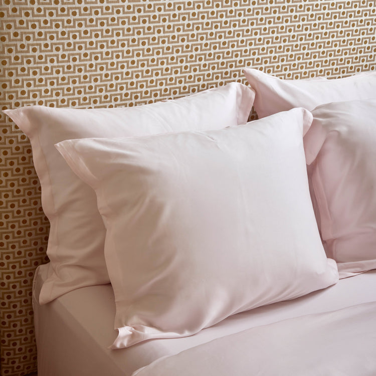 Lichtroze kussenslopen van TENCEL op een opgemaakt bed