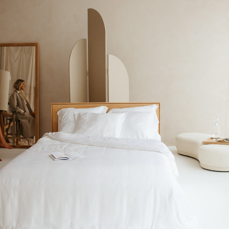 Een opgemaakt bed met een wit Bamboe hoeslaken over het matras