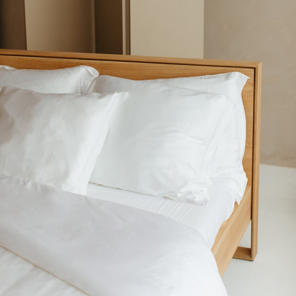 Opgemaakt bed met kussenslopen en hoeslaken van Bamboe stof in het wit.