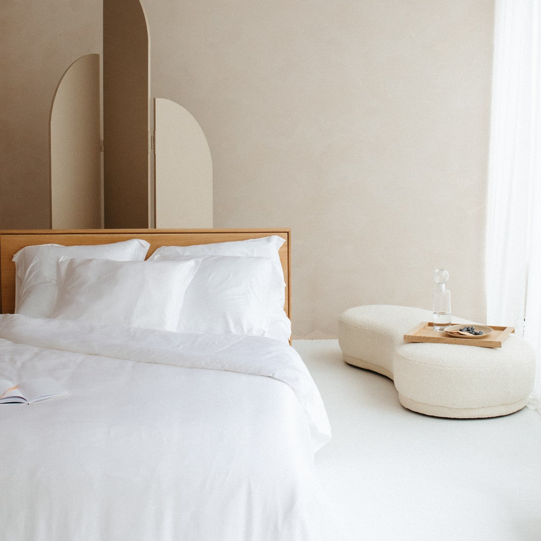 Een bed in een mooie slaapkamer met wit bamboe beddengoed. Het bed heeft vier witte bamboe kussenslopen.