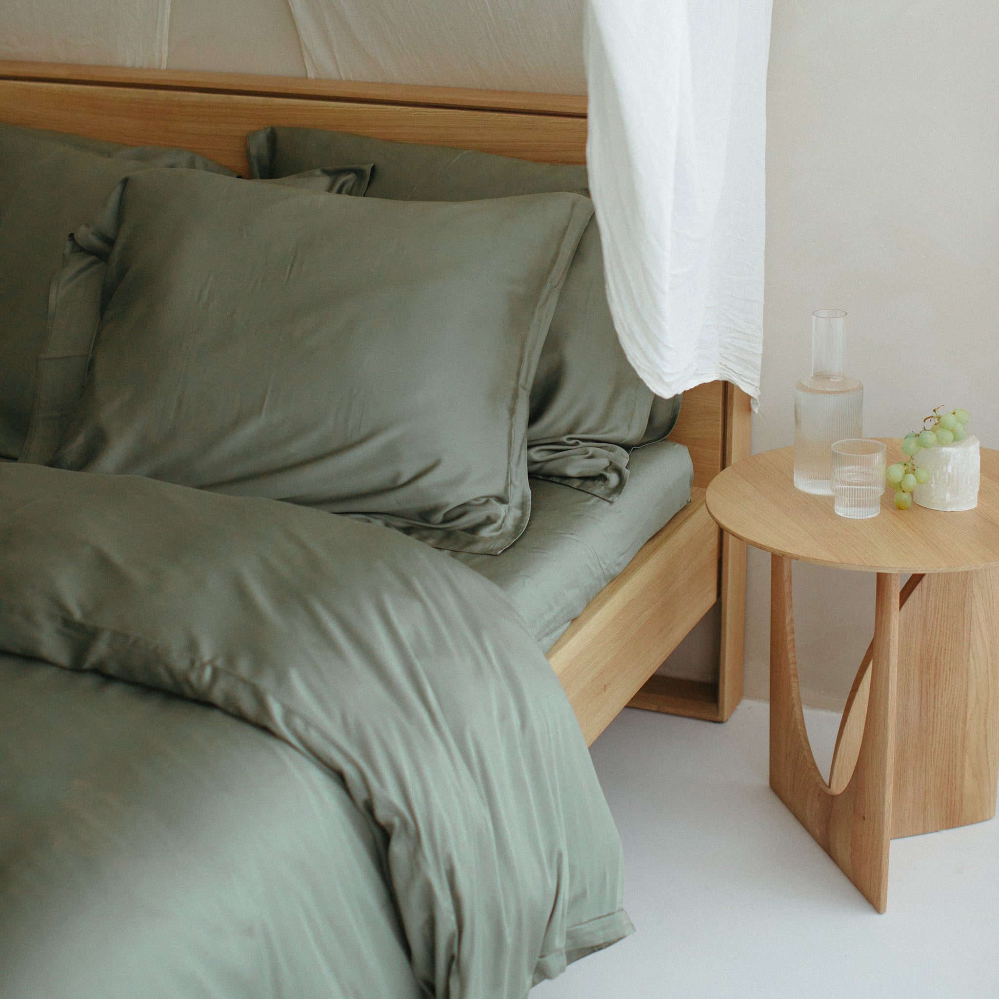 Opgemaakt bed met olijfgroen hoeslaken van de stof bamboe