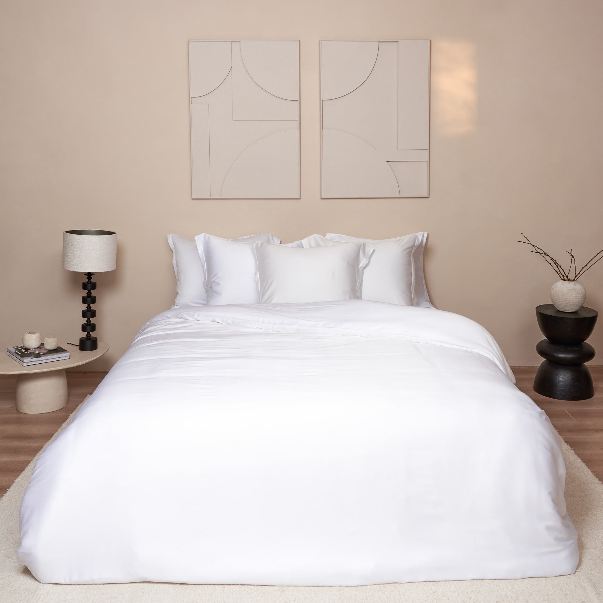 Mooie slaapkamer met wit opgemaakt beddengoed van de stof Tencel. Je ziet kussenslopen en een dekbedovertrek.