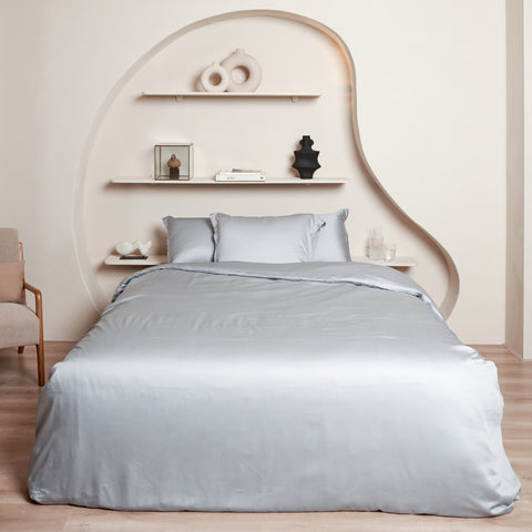 Mooi opgemaakt bed in slaapkamer. Het beddengoed is van Tencel in de kleur grijs blauw.