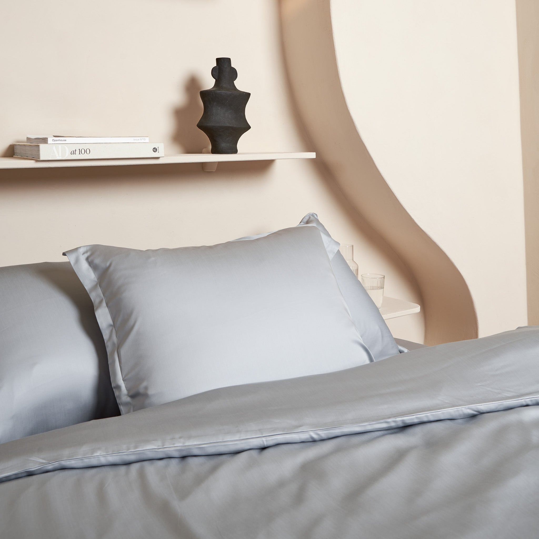 Tencel dekbedovertrek en kussenslopen op een opgemaakt bed in de kleur grijs blauw