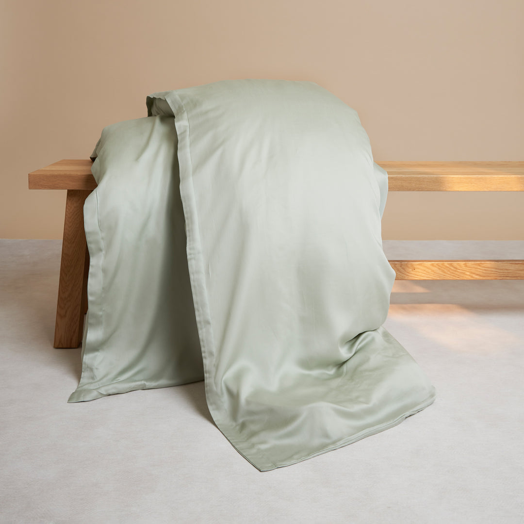Tencel dekbedovertrek in de kleur groen grijs liggend op een bankje