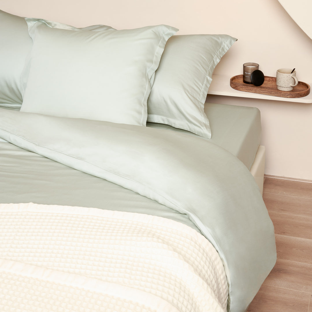Opgemaakt bed met drie Tencel kussenslopen in de kleur groen grijs