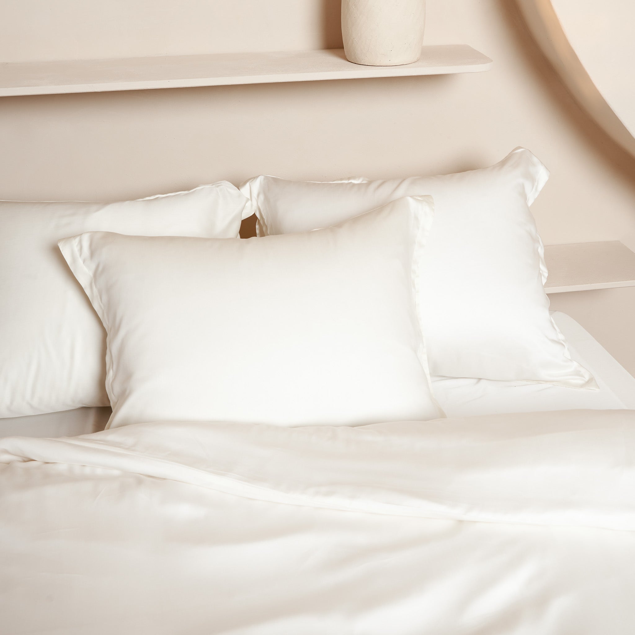Kussenslopen in de kleur offwhite gemaakt van Tencel liggend op een opgemaakt bed