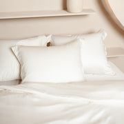 Opgemaakt bed van Tencel met hoeslaken, kussenslopen en dekbedovertrek in de kleur off white