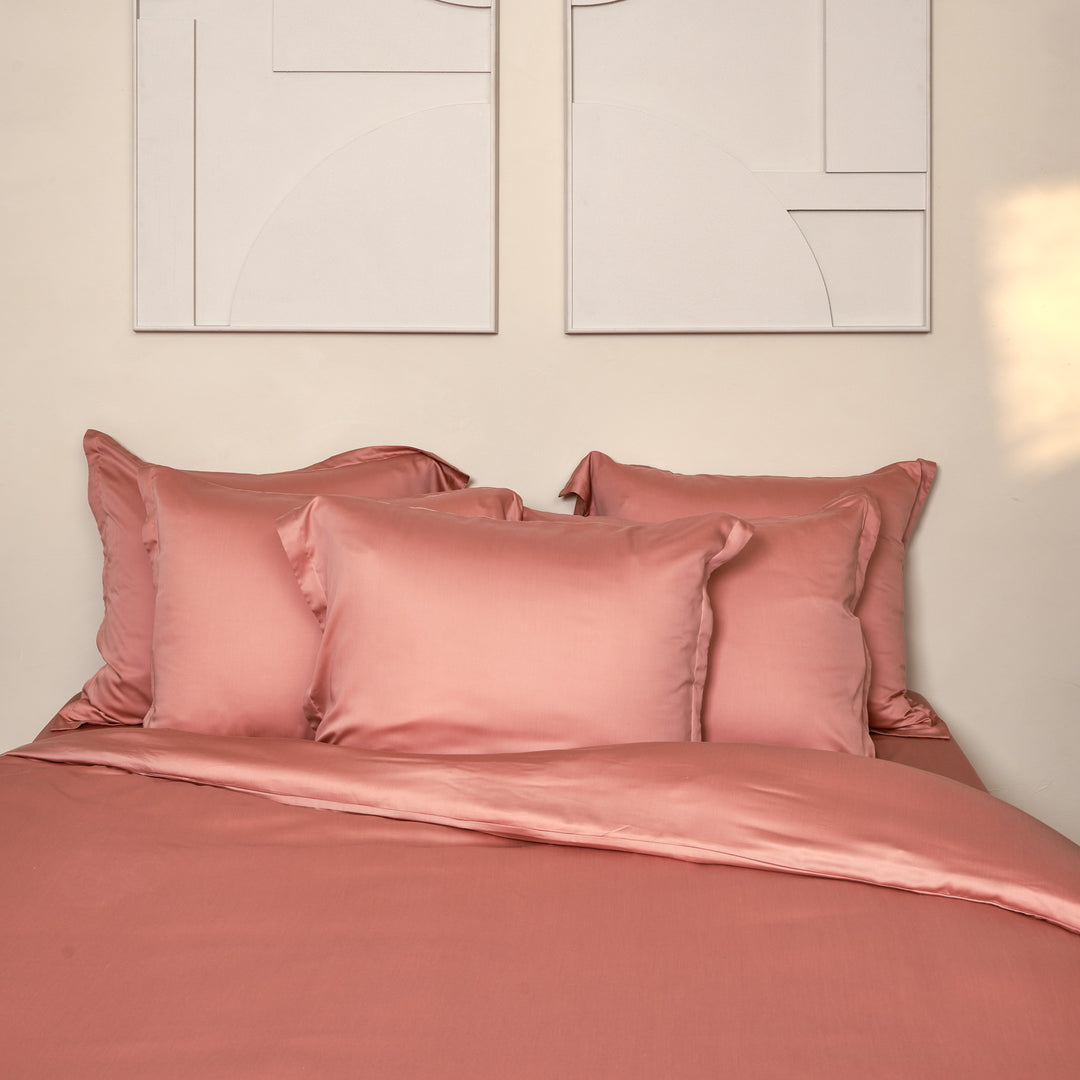 Opgemaakt bed met veel kussenslopen in de kleur terra roze