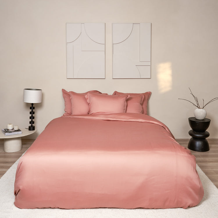 Mooi opgemaakt bed in slaapkamer. Het beddengoed en hoeslaken is van de stof Tencel en in de kleur terra roze